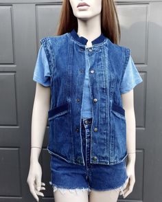 Vintage 80's denim vest with  Snap buttons down the front.  Navy blue ribbing around neck and front pockets.  Label:  Organically Grown.  .  Such a cool vest.  Has a small light whit spot on lower front. Measurements are taken with item laying flat so widths across must be doubled  Label says size small but please use measurements to see if it will work for you. Length = 23 1/2  in Across under arms =  19 1/2  in Across the bottom opening  =  18  in Please be sure to use the measurements to help Casual Medium Wash Button-up Vest, Casual Cotton Denim Vest With Snap Buttons, Casual Cotton Vest With Snap Buttons, Casual Denim Vest With Snap Buttons, Casual Button-up Vest For Everyday Wear, Blue Denim Vest With Button Closure, Everyday Medium Wash Denim Vest With Button Closure, Retro Blue Denim Vest With Pockets, Blue Cotton Denim Vest With Snap Buttons