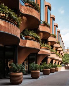 the building has many plants growing out of it's windows and balconies