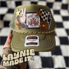 a person holding up a hat with stickers on the front and side of it