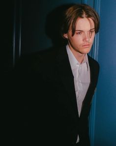 a young man in a suit and tie leaning against a wall