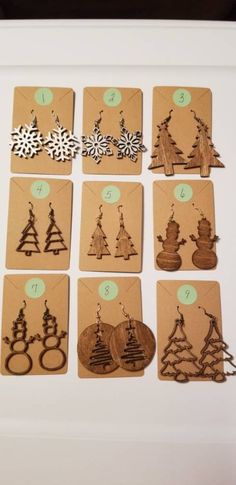 twelve wooden christmas tree earrings are shown on a white frame with green tags and numbers