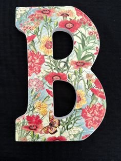 the letter b is painted with flowers and butterflies on it's sides, along with a butterfly