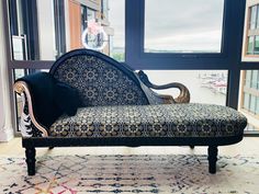 a black and white couch sitting on top of a rug next to a large window