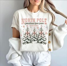 a woman wearing a north pole christmas tree farm t - shirt with pink bows on it