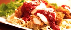 a white plate topped with pasta covered in sauce and meatballs next to lettuce