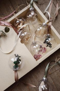 some glass ornaments are sitting in a box on the floor next to ribbons and ribbon