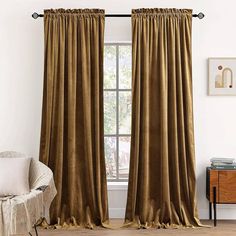 a living room with a chair and window covered in gold velvet drapes on the windowsill