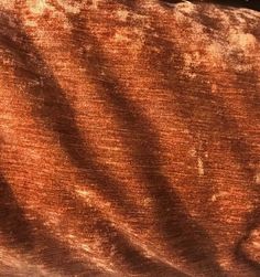 an orange and brown velvet fabric with the shadow of a bird sitting on it's back