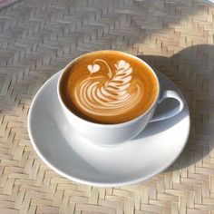 a cappuccino on a white saucer with a pattern in the foam