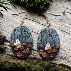 the earrings are decorated with pumpkins, ghost and trees in blue tint on wood