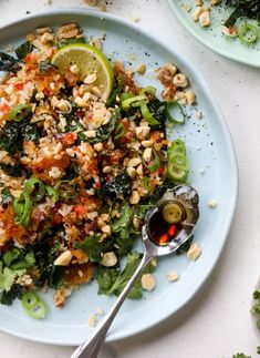 a blue plate topped with lots of food next to limes and other plates filled with food