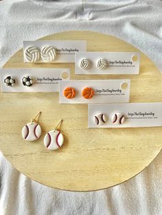 three pairs of earrings with baseball balls on them sitting on top of a wooden table