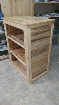 a wooden cabinet sitting on top of a tile floor next to shelves filled with tools