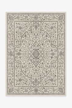 a beige and white rug with an intricate design on the bottom, in front of a gray background