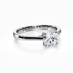 a white gold engagement ring with a round cut diamond in the center and an inscription on the side