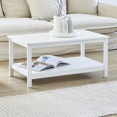 a white coffee table sitting on top of a hard wood floor next to a couch