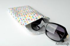 a pair of sunglasses sitting on top of a white table next to a small bag