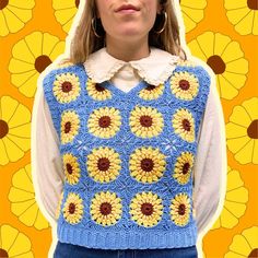 a woman wearing a blue and yellow crocheted sweater with sunflowers on it