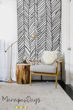 a living room with black and white wallpaper, a wooden chair and a lamp