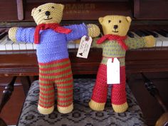 two knitted teddy bears standing next to a piano with a price tag on it