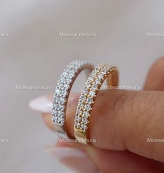 a woman's hand holding a diamond ring in her left hand, with two rows of white and yellow diamonds on it