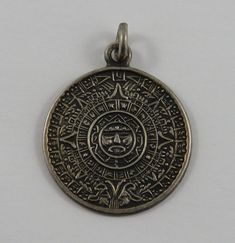 a silver pendant with an ornate design on it