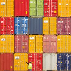 a man walking past a large stack of colorful shipping containers