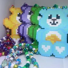 there are three different colored teddy bears next to each other with beads on the ground