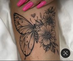 a woman's leg with a butterfly and flowers tattoo on it