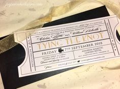 a ticket is laying on top of a black and white tablecloth with gold foil