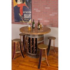 a wine barrel table with stools and bottles on it in front of a brick wall