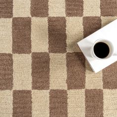 a cup of coffee sitting on top of a brown and white checkered table cloth