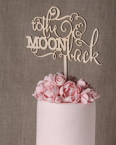 a pink cake with white frosting and flowers on top that says to the moon back