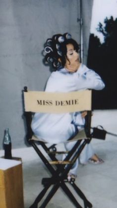 a woman sitting in a director's chair next to a sign that says miss demie