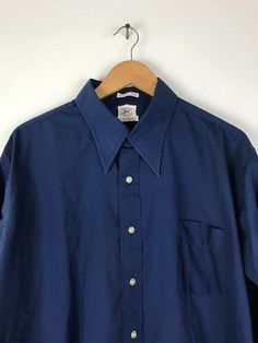 "-Description- >men's dark blue french cuff dress shirt >collared >button front >open pocket on the front >original print/stamp on bottom front of shirt >size XXL 17.5 >perfect for a formal event! >condition: ok condition - a good amount of wear on the collar - please see all photos before purchase >color(s): blue >fabric(s): 65 polyester / 35 cotton >brand: enro >care: machine wash -Measurements- >size: XXL 17.5 ✩ all measurements are taken with the item l Blue Shirt With Cuffed Sleeves And Spread Collar, Classic Blue Shirt With Cuffed Sleeves, Vintage Collared Formal Shirt, Vintage Formal Collared Shirt, Vintage Long Sleeve Business Shirt, Vintage Blue Shirt For Workwear, Vintage Blue Shirt For Work, Dark Blue Dress Shirt, Print Stamp