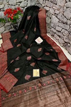 This latest collection is in a black and red color combination, a pure tussar silk banarasi saree with golden zari and meenakari work, and in an alluring meenar butta work on the body and traditional meenakari work on the pallu and the border and all over. Color: A shade of black and red color Technique: A pure and refined hand-done work of border with meenakari zari work and traditional meena butta work Fabric: Tussar Quality: IndyVogue's Assurance of Silk Mark Certification Note: Comes with co