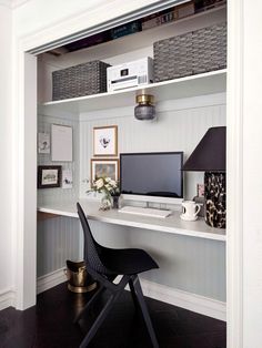 a desk with a computer, lamp and pictures on the wall in front of it