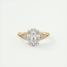 an oval cut diamond ring with two side stones on the band, set in yellow gold