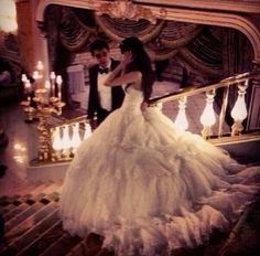 a bride and groom standing on stairs in front of a chandelier with candles