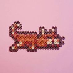 an orange and white beaded animal on a pink background