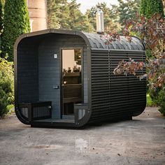 an outdoor sauna is shown in the middle of some bushes and trees with its door open