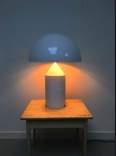 a white lamp sitting on top of a wooden table next to a light blue wall