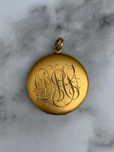 The vintage gold filled monogrammed locket exudes timeless elegance with its classic design and personalized touch. Crafted with precision and attention to detail, this exquisite piece features a sturdy gold filled construction, ensuring durability and a lustrous shine that will last for years to come. The locket showcases a vintage-inspired aesthetic, characterized by its ornate engravings and intricate detailing. The surface of the locket is adorned with a delicate monogram, adding a touch of personalization and making it a truly unique piece. Whether it bears your initials or someone dear to your heart, the monogram adds sentimental value and makes this locket the ultimate keepsake. With a hinge that opens smoothly and securely, the locket reveals two compartments to hold cherished phot Locket Tattoos, Locket Gold, Antique Locket, Inspired Aesthetic, Statement Pendant, Antique Stores, Wedding Anniversary Gifts, Vintage Charms, The Vintage