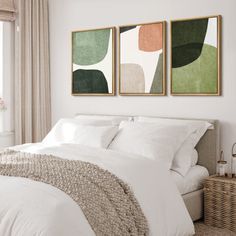 two paintings on the wall above a bed in a bedroom with white sheets and pillows