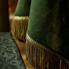 two green velvet lamps with gold fringes on them