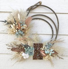 two wreaths with feathers and flowers hanging on a wall