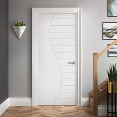 a white door in the corner of a room next to a stair case and potted plant