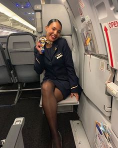 a woman is sitting on an airplane and holding a small item in her hand as she looks at the camera