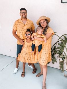 a family poses for a photo in front of a wall with a potted plant