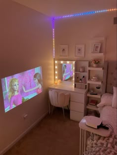 a bedroom with a bed, desk and television in it's corner that is turned on